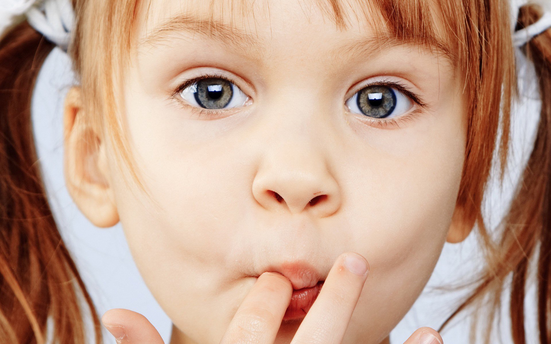 Close-up photography of a young child with wide eyes and fingers near her mouth, featured as an HD PC desktop wallpaper and background.