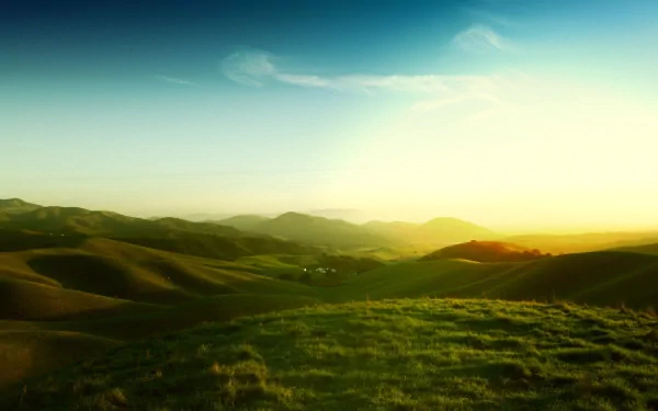 HD desktop wallpaper showcasing a tranquil landscape of rolling hills under a clear sky at sunrise, capturing the serene beauty of nature.