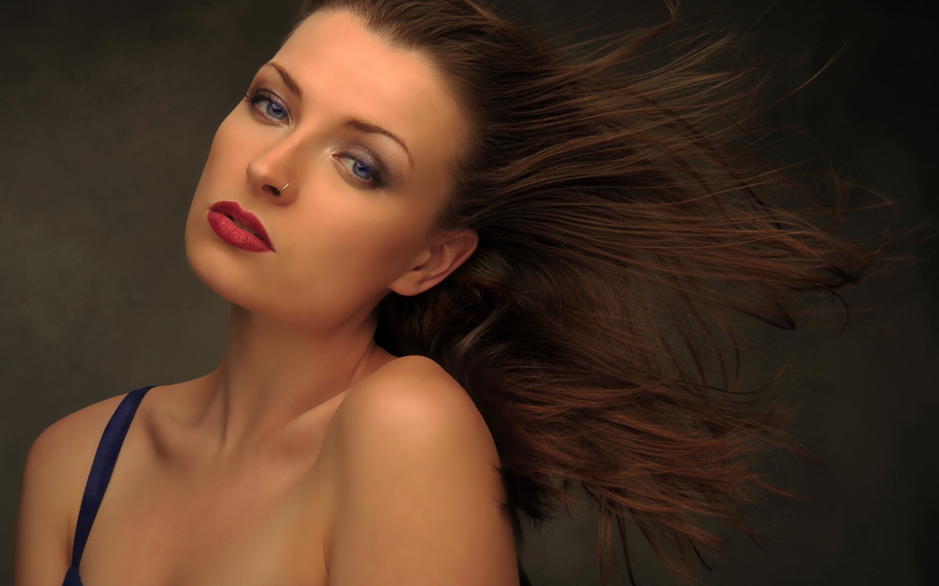 HD PC desktop wallpaper featuring a pretty woman with flowing hair and striking makeup against a dark background.