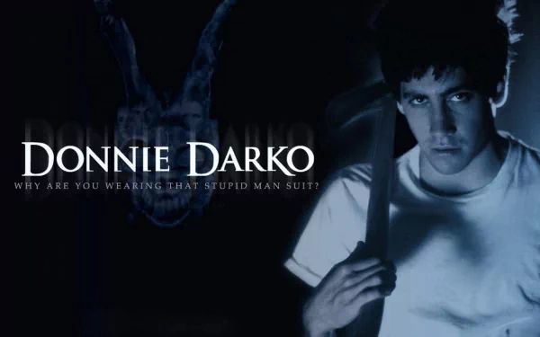 HD desktop wallpaper and background image from the movie Donnie Darko, featuring Jake Gyllenhaal with a dark and intense expression, holding an object, the title, and the text Why are you wearing that stupid man suit?.