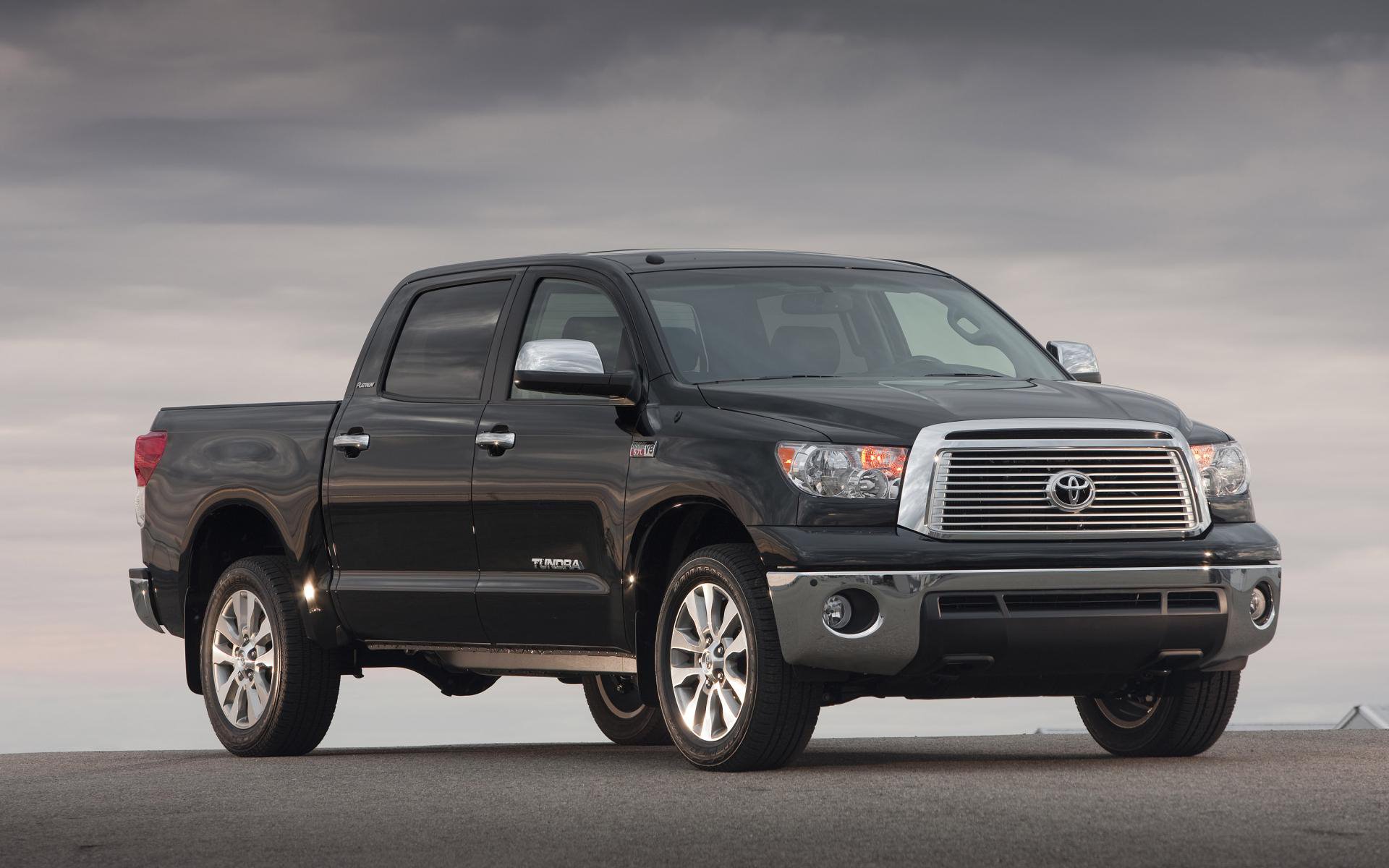 HD PC desktop wallpaper featuring a black Toyota off-road vehicle parked on a flat, open surface under a cloudy sky.