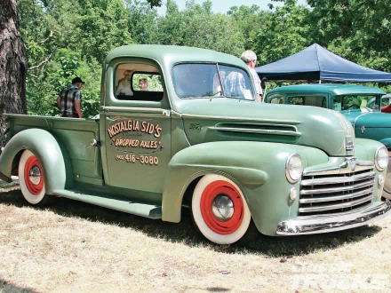 Vintage green Ford pickup truck with red wheels parked on grass, featured in an HD PC desktop wallpaper showcasing classic vehicles.