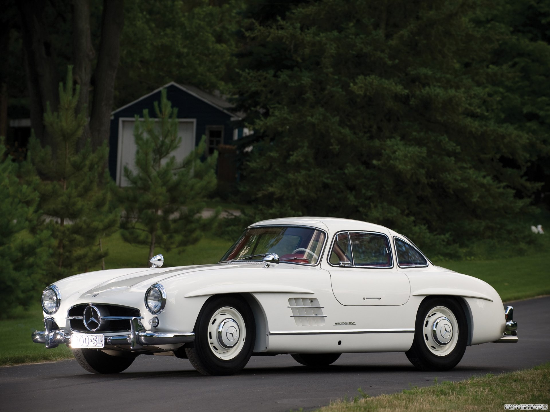 HD desktop wallpaper featuring a classic white Mercedes-Benz 300SL parked on a road with a lush green forest background.