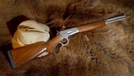 Big Horn Armory Model 89 lever-action rifle with cartridges laid on fur, a man-made firearm arranged as an HD PC desktop wallpaper and background.
