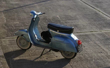 HD desktop wallpaper featuring a vintage blue scooter parked on a concrete surface under natural sunlight.