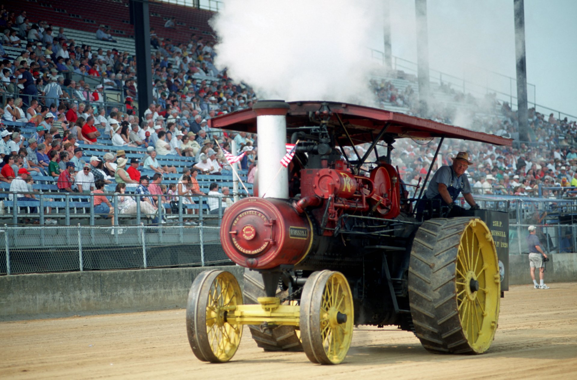 4K Ultra HD image of a vintage steam-powered tractor in motion at a crowded outdoor event, captured with clear detail and vibrant colors.