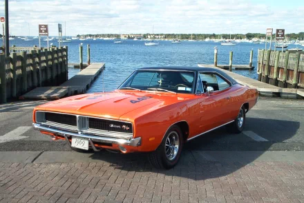 Orange Dodge Charger (Chrysler) parked at a waterfront pier — classic Dodge vehicle in an HD PC desktop wallpaper and background.