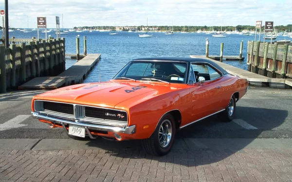 Orange Dodge Charger (Chrysler) parked at a waterfront pier — classic Dodge vehicle in an HD PC desktop wallpaper and background.