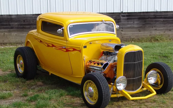 A vibrant yellow hot rod car with flame decals and exposed engine, captured outdoors on grass; a high-definition PC desktop wallpaper and background.