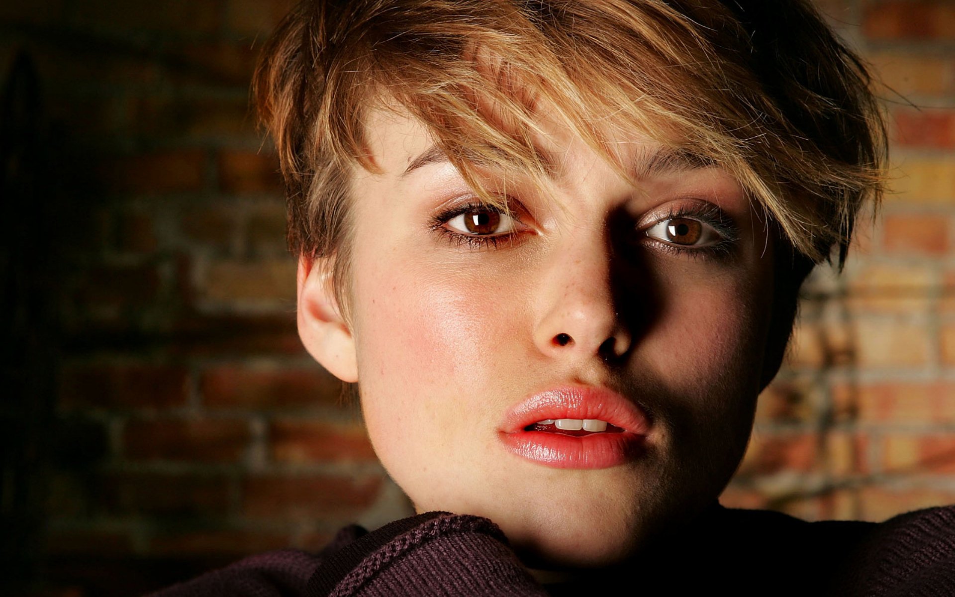 A close-up of Keira Knightley, showcasing her expressive face and short hair against a textured brick background. This HD image serves as a striking desktop wallpaper.
