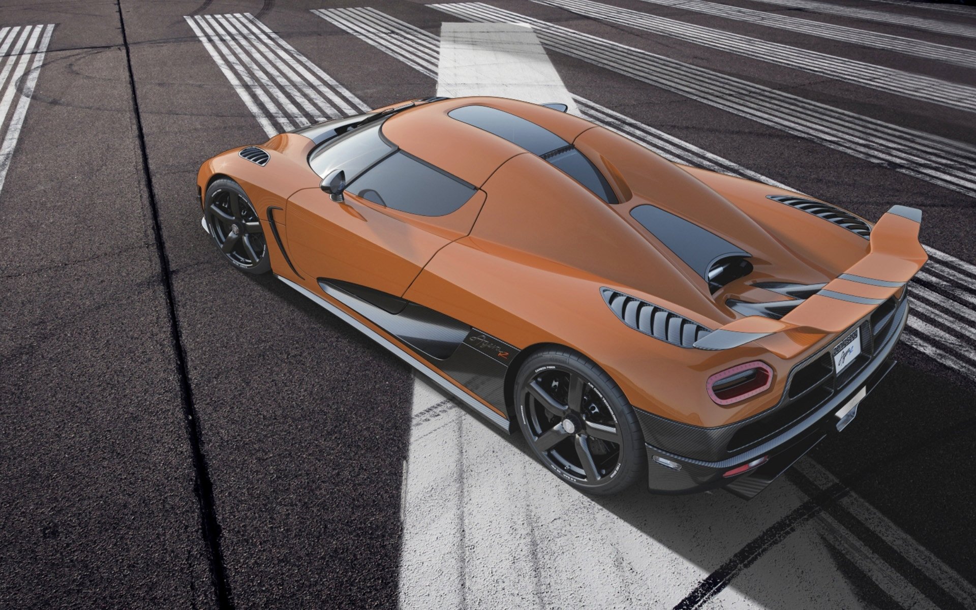 A striking Koenigsegg Agera R parked on a sleek surface, showcasing its aerodynamic design and vibrant orange color. An eye-catching HD desktop wallpaper for automotive enthusiasts.