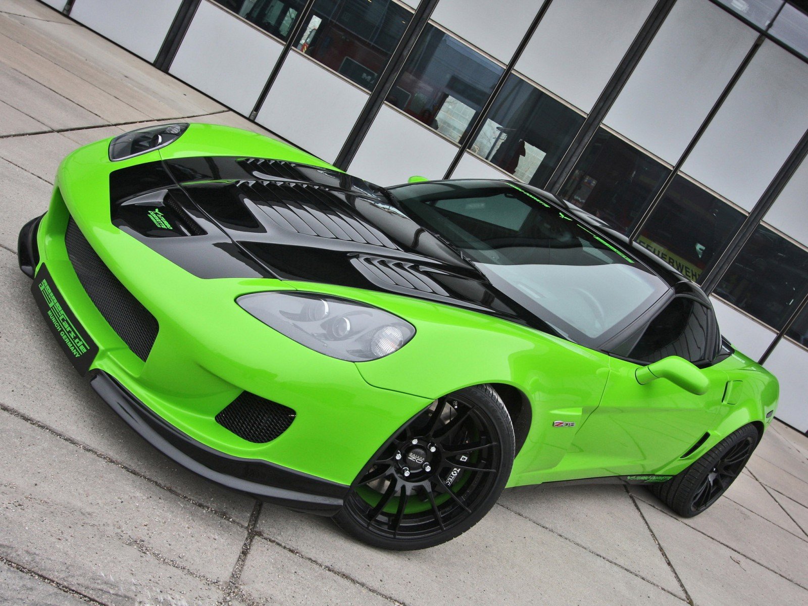 HD desktop wallpaper featuring a vibrant green Chevrolet Corvette parked on a concrete surface in front of a modern glass building.