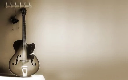 HD desktop wallpaper featuring a classic guitar hanging on a wall hook, with a soft beige background and minimalistic composition.