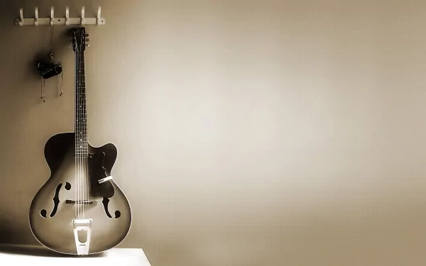 HD desktop wallpaper featuring a classic guitar hanging on a wall hook, with a soft beige background and minimalistic composition.
