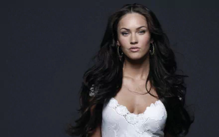 HD wallpaper of celebrity Megan Fox with dark, flowing hair, wearing a white lace dress against a dark background.