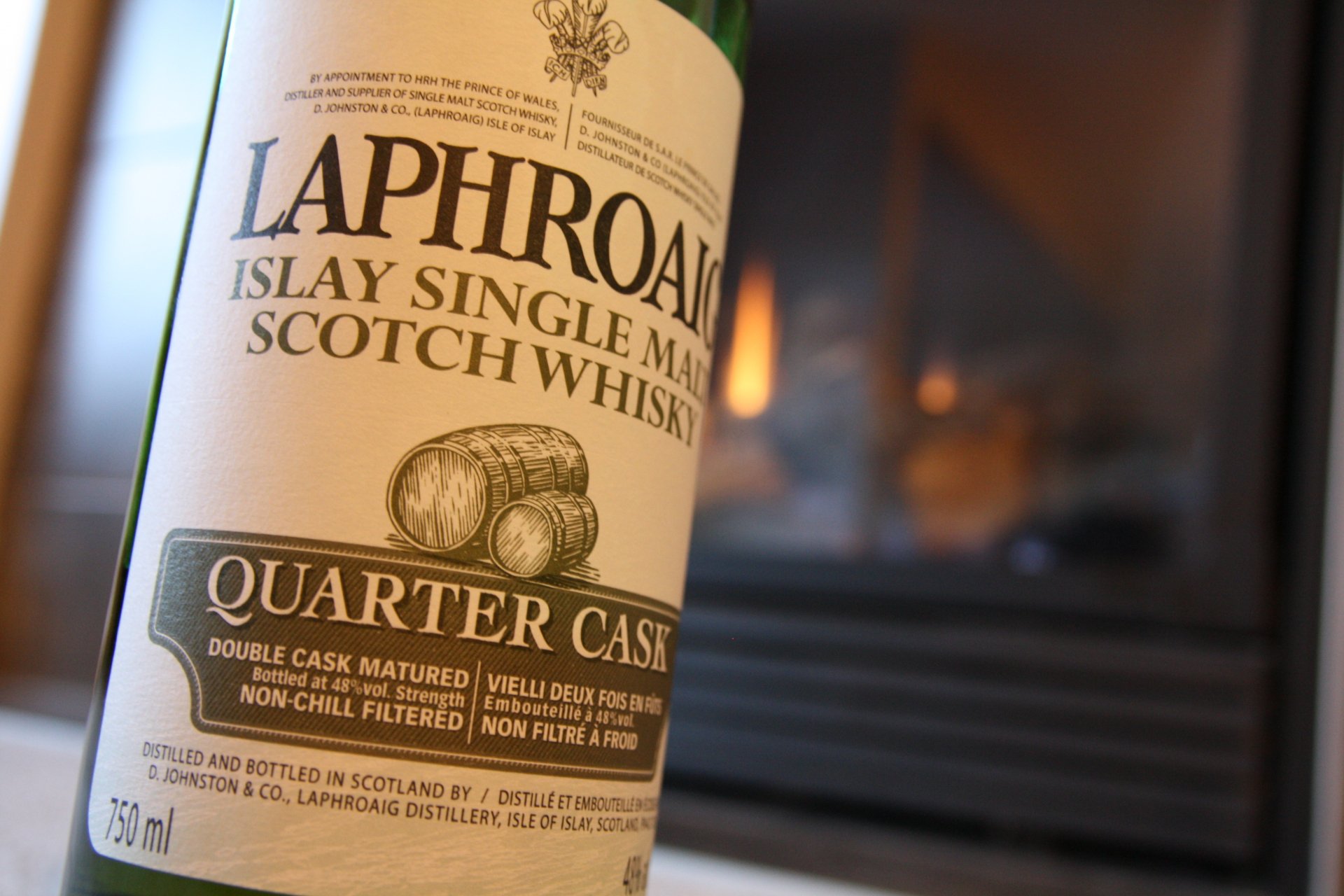 Close-up of Laphroaig Islay Single Malt Scotch Whisky Quarter Cask label by a warm fireplace, 4K Ultra HD PC desktop wallpaper background — food, whisky.
