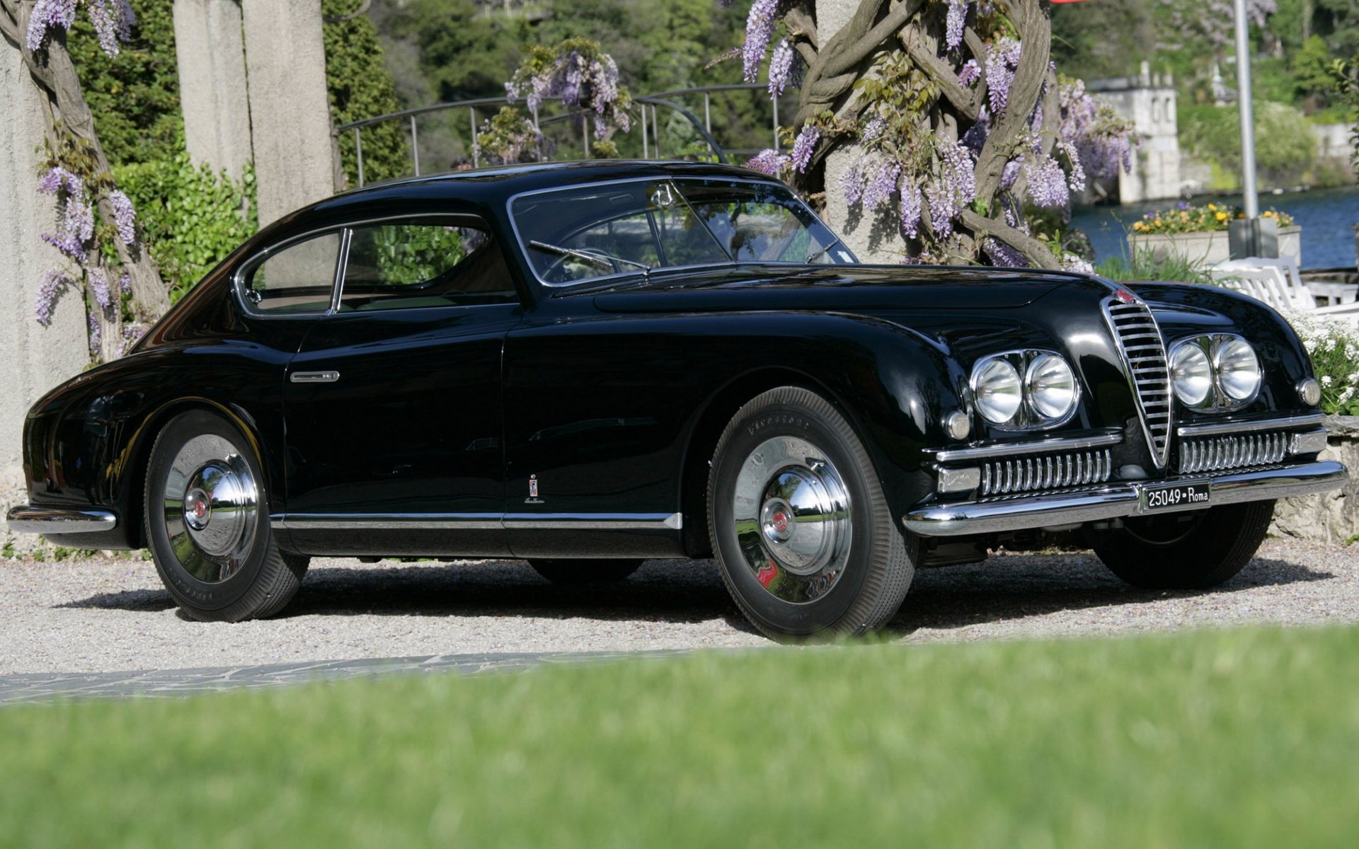 HD PC desktop wallpaper background showing a sleek black vehicle, Alfa Romeo 6C 2500 classic coupe parked beside a lakeside garden.