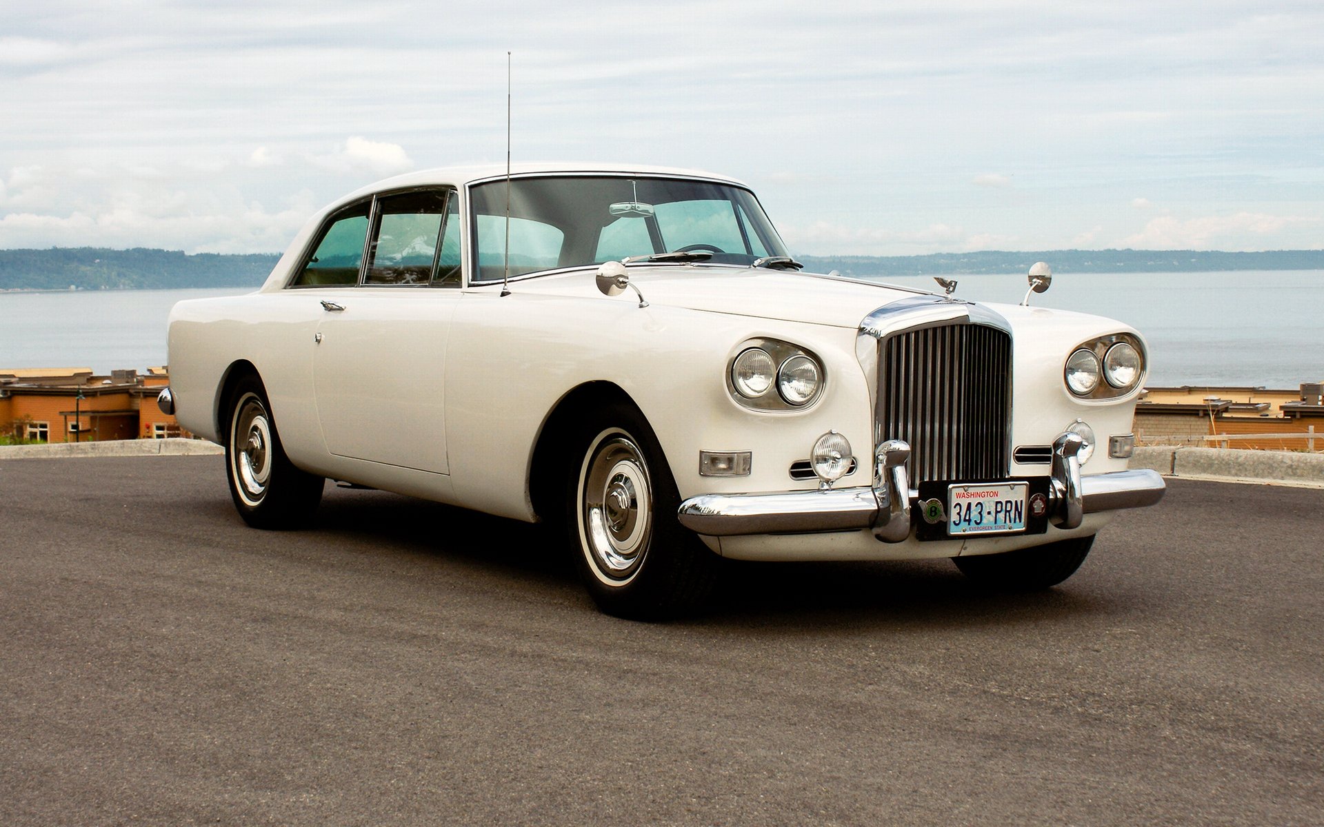 HD PC desktop wallpaper featuring a classic white Bentley vehicle parked near a waterfront under a cloudy sky.