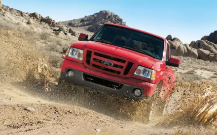 A red Ford Ranger vehicle driving through a rugged, rocky desert terrain with dust and dirt flying, captured in HD as a dynamic desktop wallpaper.
