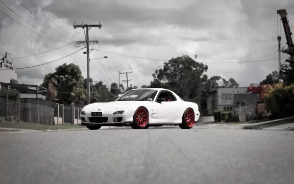 HD PC desktop wallpaper background: white Mazda sports car with red rims parked on an industrial street under a cloudy sky.