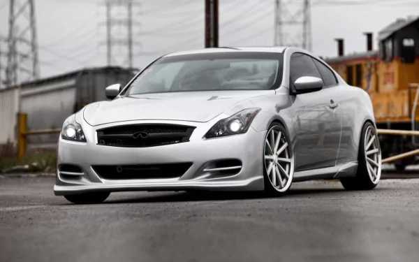 Silver Infiniti coupe on wet industrial lot with low stance and aftermarket wheels — HD PC desktop wallpaper/background