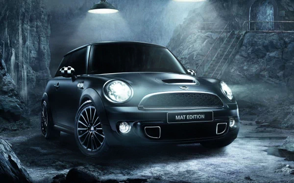 A sleek Mini Cooper in a matte finish, showcased in a dramatic underground setting. This HD wallpaper features stylish lighting and an industrial backdrop.