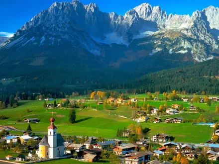 Photography landscape: HD PC desktop wallpaper background of a green Alpine valley village with church steeple beneath towering snow-capped mountains.