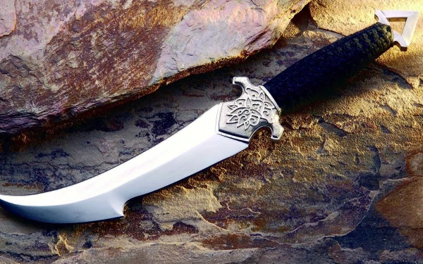 HD desktop wallpaper featuring a finely crafted knife with intricate design, resting on a textured rock surface.