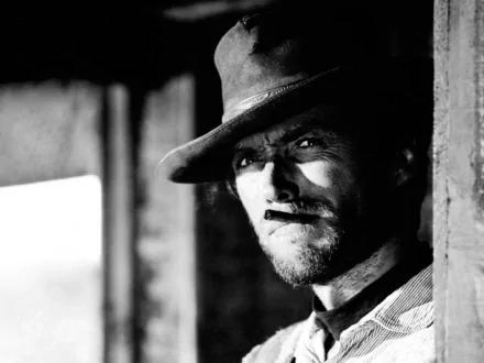 Black and white HD desktop wallpaper of Clint Eastwood in a classic western attire, with a rugged expression and a cigarette in his mouth.