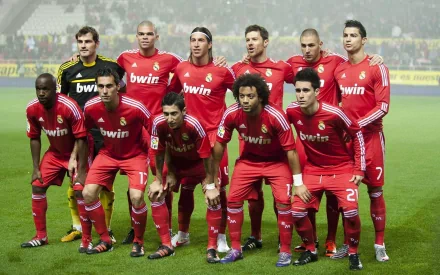 The image shows Real Madrid C.F. players in red uniforms posing together on a football field for a group photo. The HD image can be used as a desktop wallpaper and background.