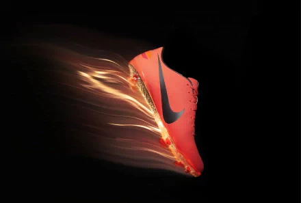 A dynamic HD desktop wallpaper featuring a vibrant Nike shoe, captured mid-motion with streaks of light, showcasing its man-made design and energetic appeal.