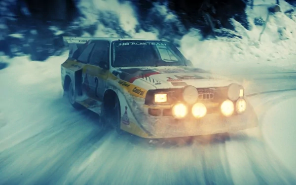 HD desktop wallpaper featuring a vintage Audi rally car speeding through a snowy, mountainous landscape with bright headlights cutting through the blur.