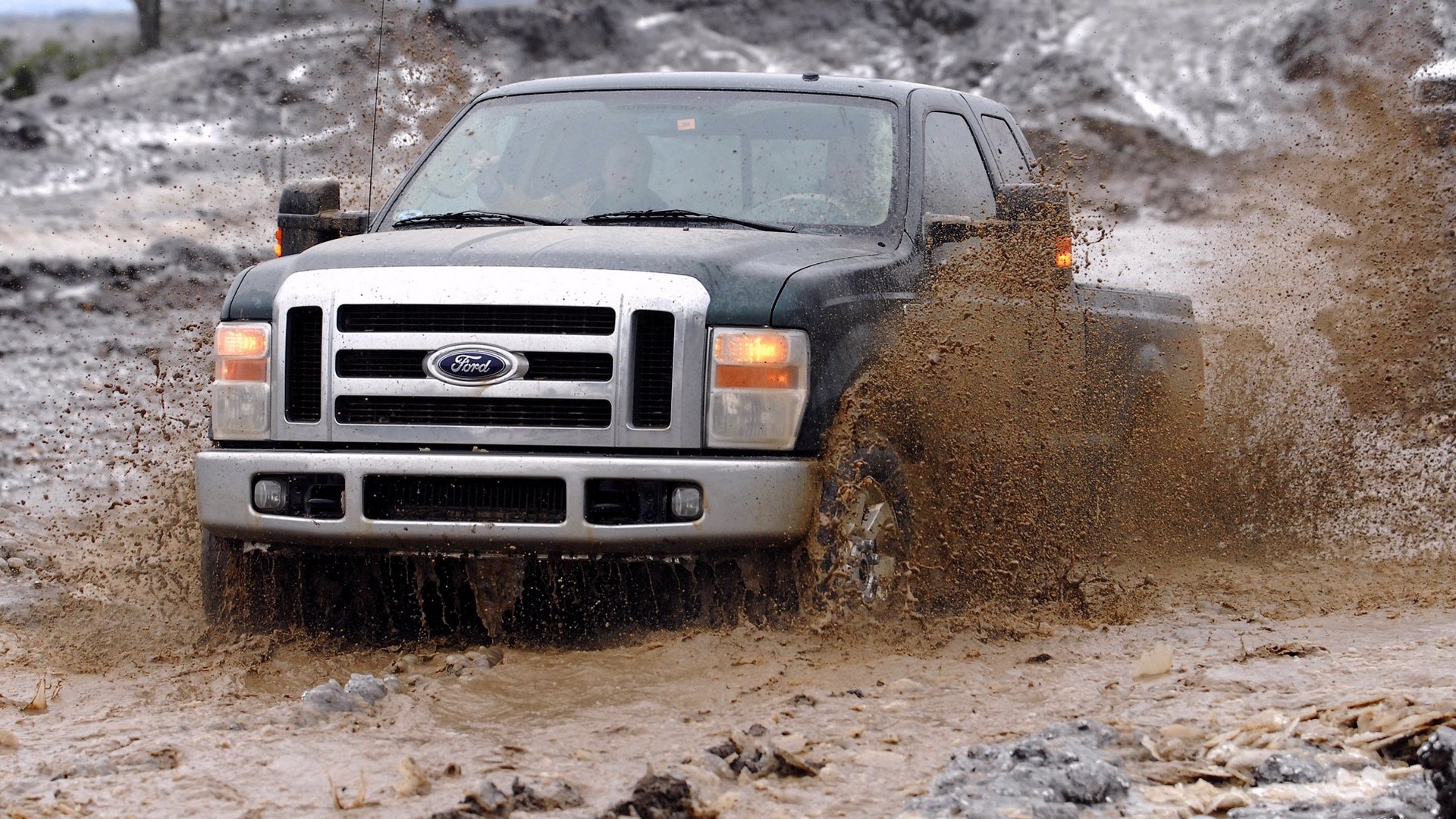 Ford Super Duty truck driving through muddy terrain, captured in an HD PC desktop wallpaper showcasing rugged off-road capability.
