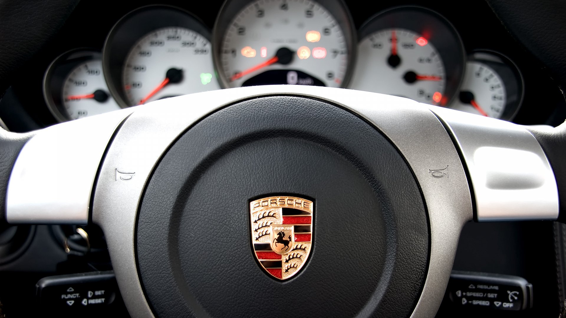 Close-up of a Porsche steering wheel and dashboard gauges, captured in high definition for a PC desktop wallpaper background.