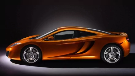Sleek orange McLaren sports car side profile on a dark backdrop — HD PC desktop wallpaper/background featuring a high-performance vehicle.