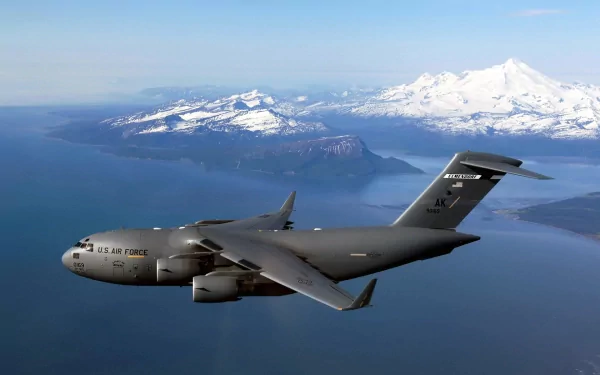 Military Boeing C-17 Globemaster III aircraft flying over mountainous terrain, captured in a high-definition desktop wallpaper image.
