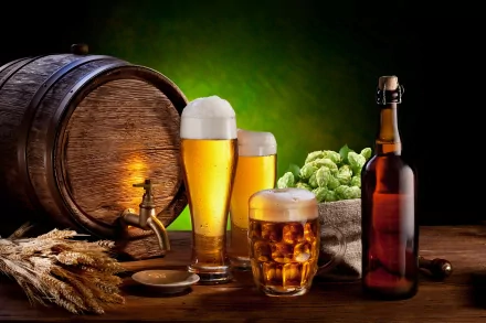 4K Ultra HD wallpaper featuring a beer bottle, two glasses of beer with foam, a wooden barrel, hops, and wheat on a rustic wooden surface against a green background.