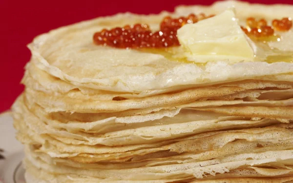 HD desktop wallpaper featuring a stack of thin crêpes topped with butter and red caviar against a vibrant red background.