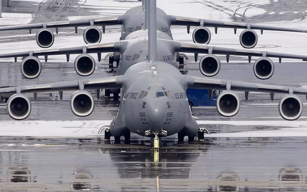 A lineup of Boeing C-17 Globemaster III military aircraft from the Air Force on a wet runway, captured in HD for a desktop wallpaper background.