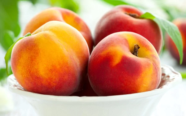 HD PC desktop wallpaper featuring a close-up of ripe, colorful peaches in a white bowl with a soft green background.