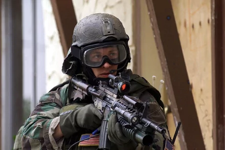 A soldier wearing tactical gear and goggles aims a firearm in a military setting. The image is a high-definition desktop wallpaper and background.
