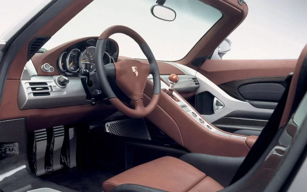 A stunning HD desktop wallpaper showcasing the interior of a Porsche Carrera GT, featuring sleek design, leather seats, and a modern dashboard. Experience luxury and performance in style.