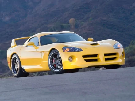 A striking yellow Dodge Viper parked on a winding road, with rugged mountains in the background, showcasing its sleek design and performance-oriented features in high definition.