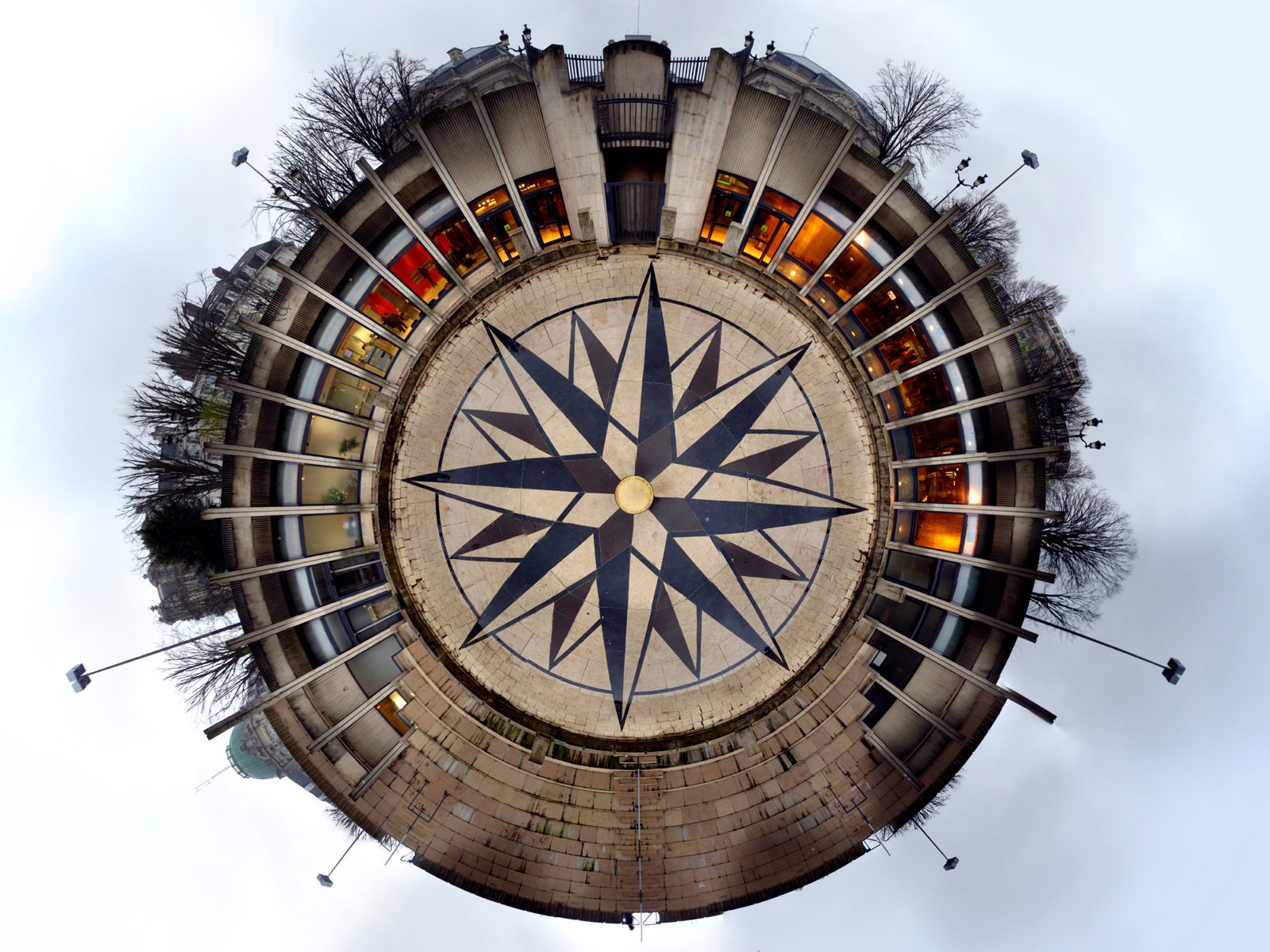 A captivating artistic representation of a compass design within a circular stone structure, surrounded by nature and urban elements, creating a serene HD desktop wallpaper.
