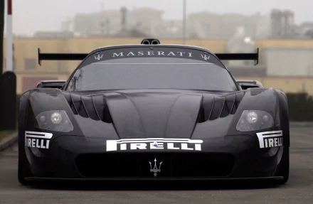 A sleek black Maserati racing vehicle, showcasing its aerodynamic design and bold branding, set against a muted background, creating an impressive HD desktop wallpaper.