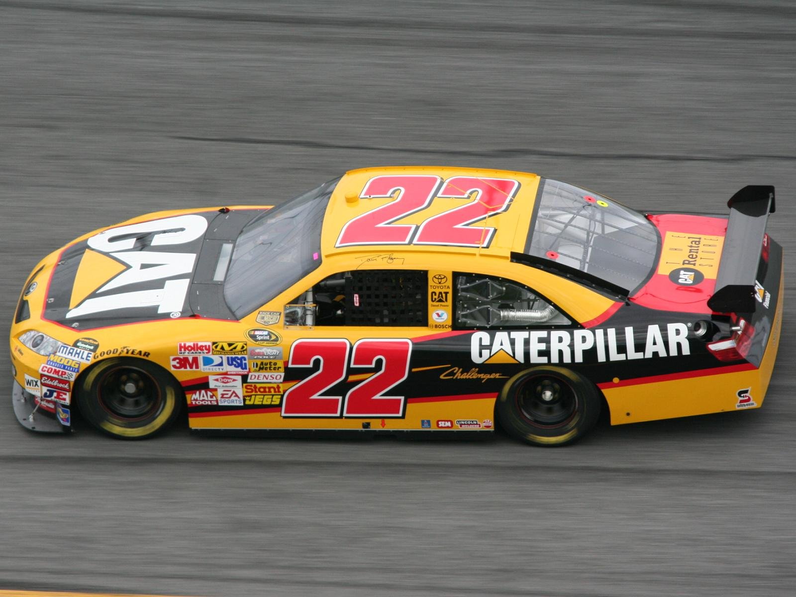 A vibrant, high-definition image of a racing vehicle, prominently featuring the number 22 and Caterpillar branding, set against a blurred racetrack background.