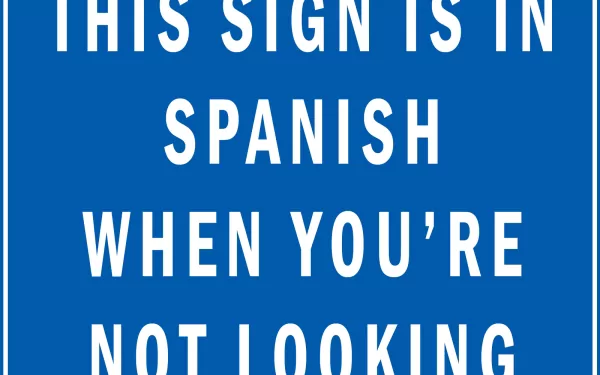 Funny HD wallpaper with a blue background featuring white text that says, This sign is in Spanish when you're not looking.