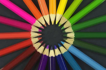 HD desktop background featuring a vibrant circular arrangement of colored pencils, showcasing a full spectrum of colors against a black backdrop.