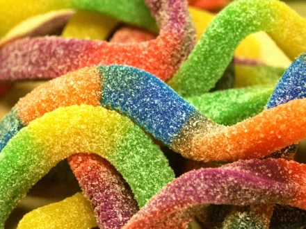 HD desktop wallpaper featuring a colorful array of sugary, rainbow-colored candy strips intertwined, highlighting their vibrant hues and sugary texture. Tags: sweets, food, candy.