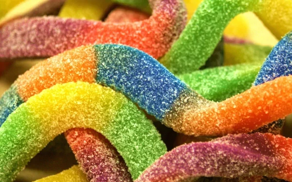 HD desktop wallpaper featuring a colorful array of sugary, rainbow-colored candy strips intertwined, highlighting their vibrant hues and sugary texture. Tags: sweets, food, candy.